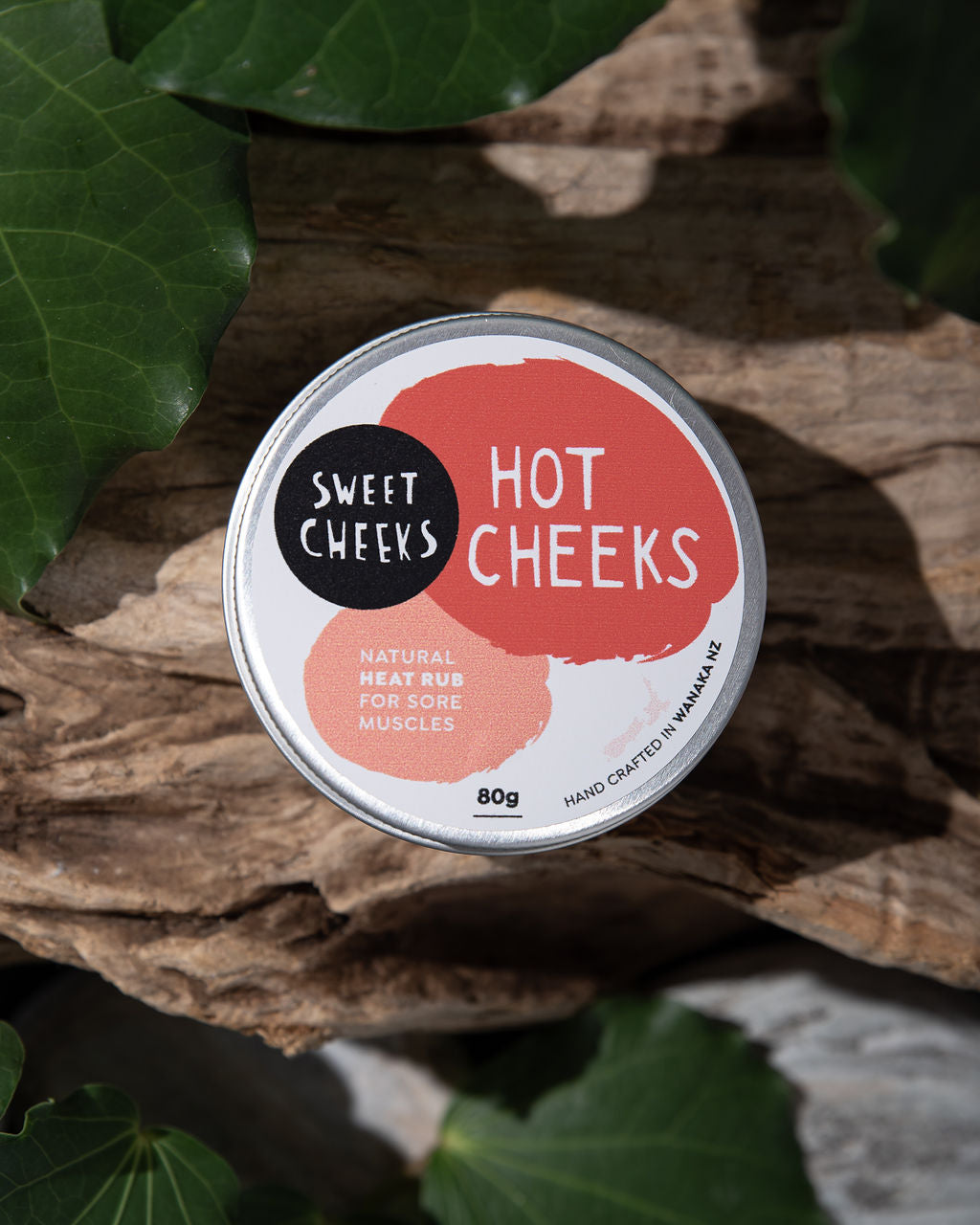 Tin of 'Hot Cheeks' natural heat rub on a leafy background