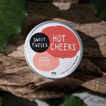 Tin of 'Hot Cheeks' natural heat rub on a leafy background