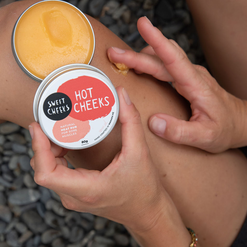 Person applying 'Hot Cheeks' cream to their leg with a container of the product.