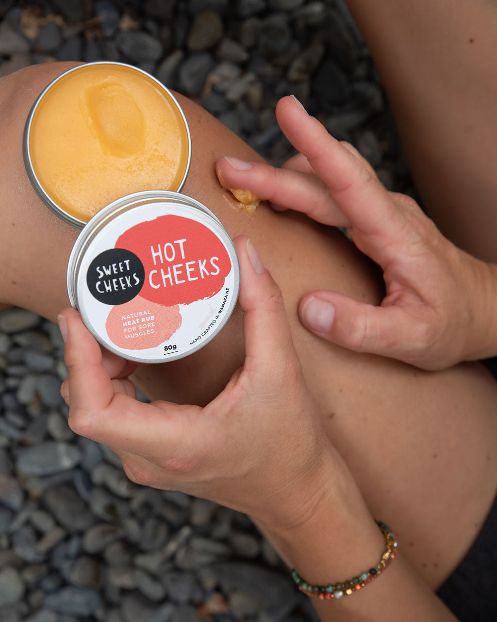 Person applying 'Hot Cheeks' cream to their leg with a container of the product.