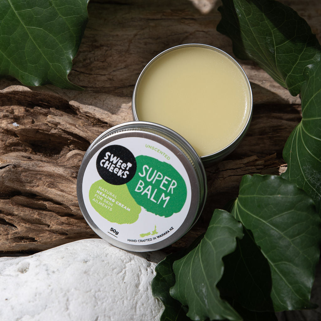 Super balm in a metal tin with green leafy background