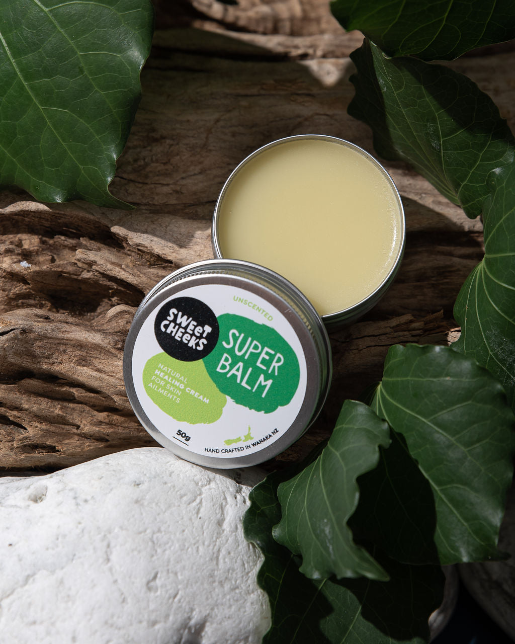 Super balm in a metal tin with green leafy background
